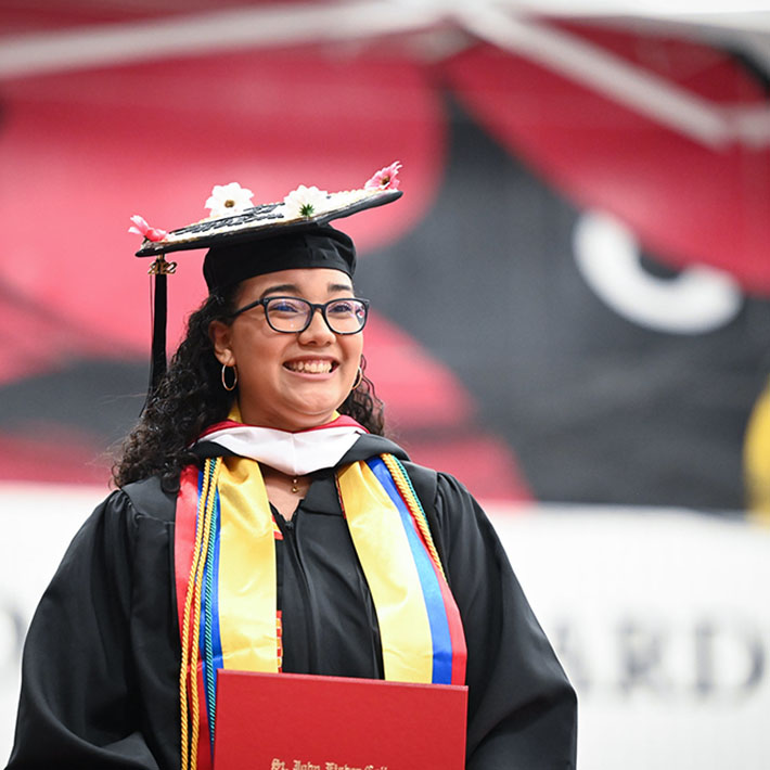 A student in cap and gown smiles during commencement.