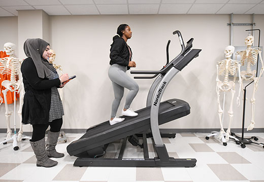 Two students, one on treadmill as part of athletic studies program.